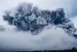 Visiteurs anonymes marchant parmi fondations arasées et collines volcaniques en plein jour