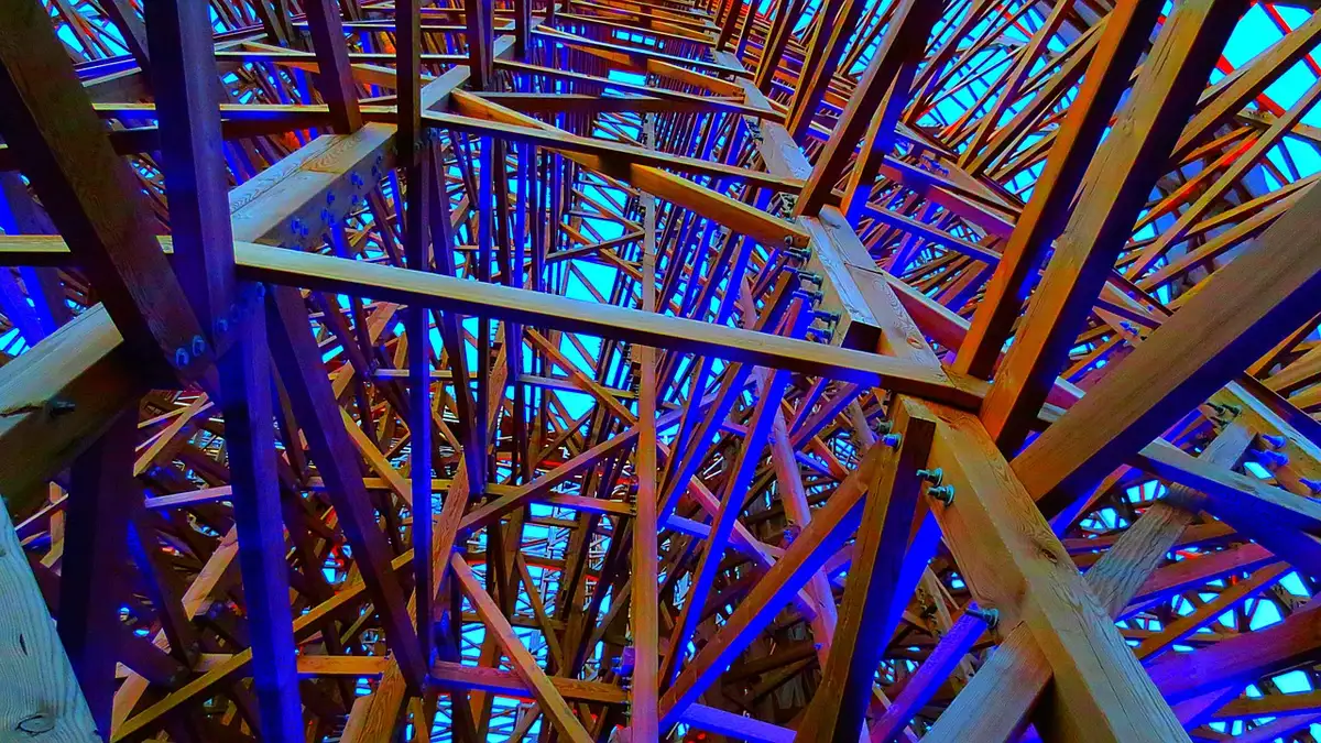 Gros plan d'une structure de montagne russe en bois montrant rails et vibrations