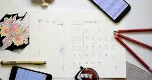 Bureau lumineux avec ordinateur montrant plusieurs calendriers et mains anonymes