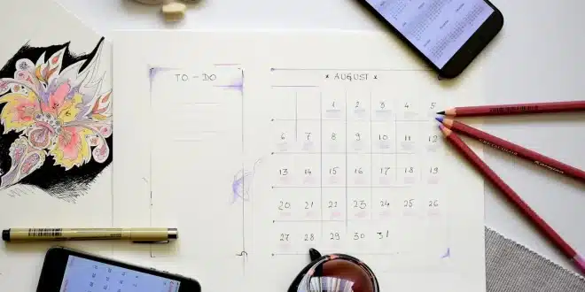 Bureau lumineux avec ordinateur montrant plusieurs calendriers et mains anonymes