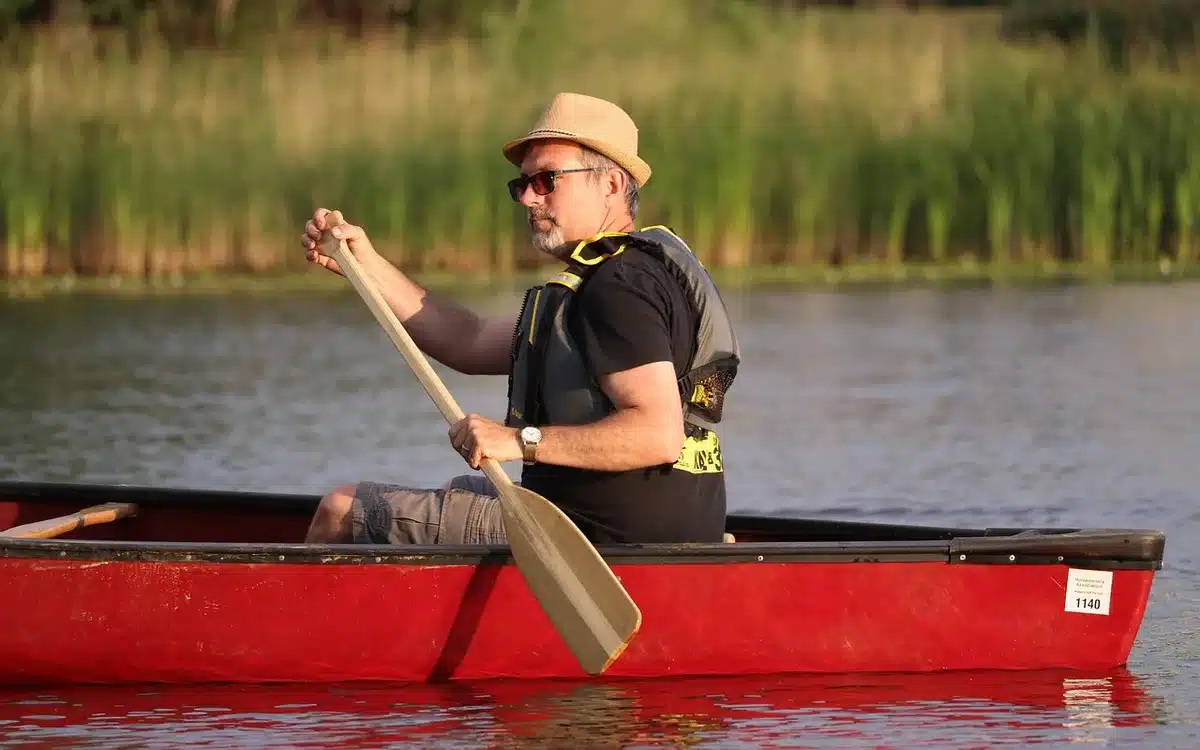 Canoë descendant un méandre de rivière entouré de collines boisées