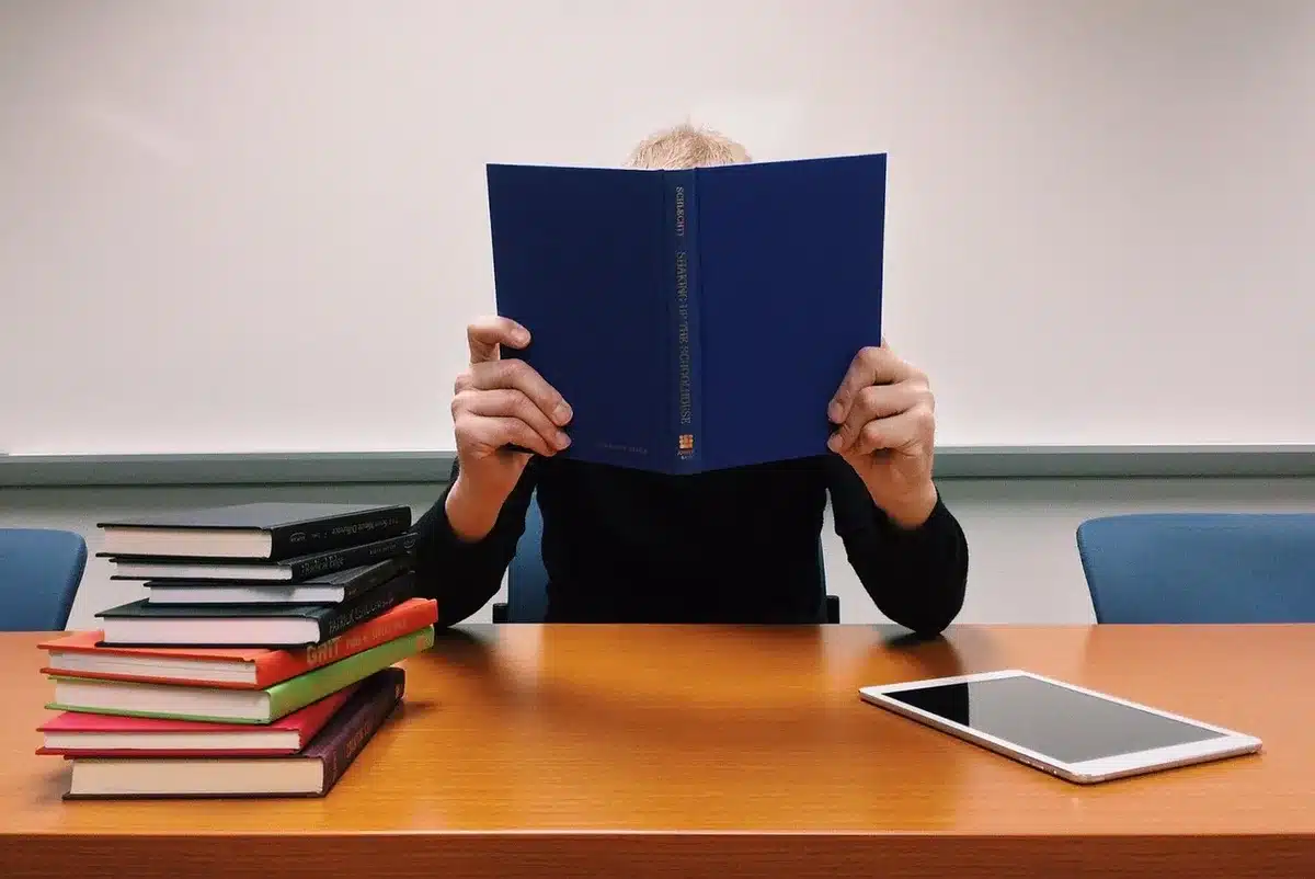 Personne lisant un livre avec écouteurs posés à côté
