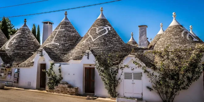 Rue pavée aux maisons blanches et trulli en arrière-plan, petit café en terrasse