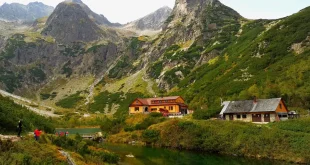 Bord d'un lac de montagne avec une route sinueuse, randonneurs et village en plein jour