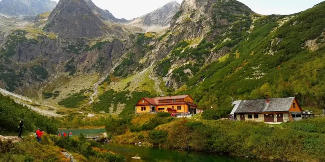 Bord d'un lac de montagne avec une route sinueuse, randonneurs et village en plein jour