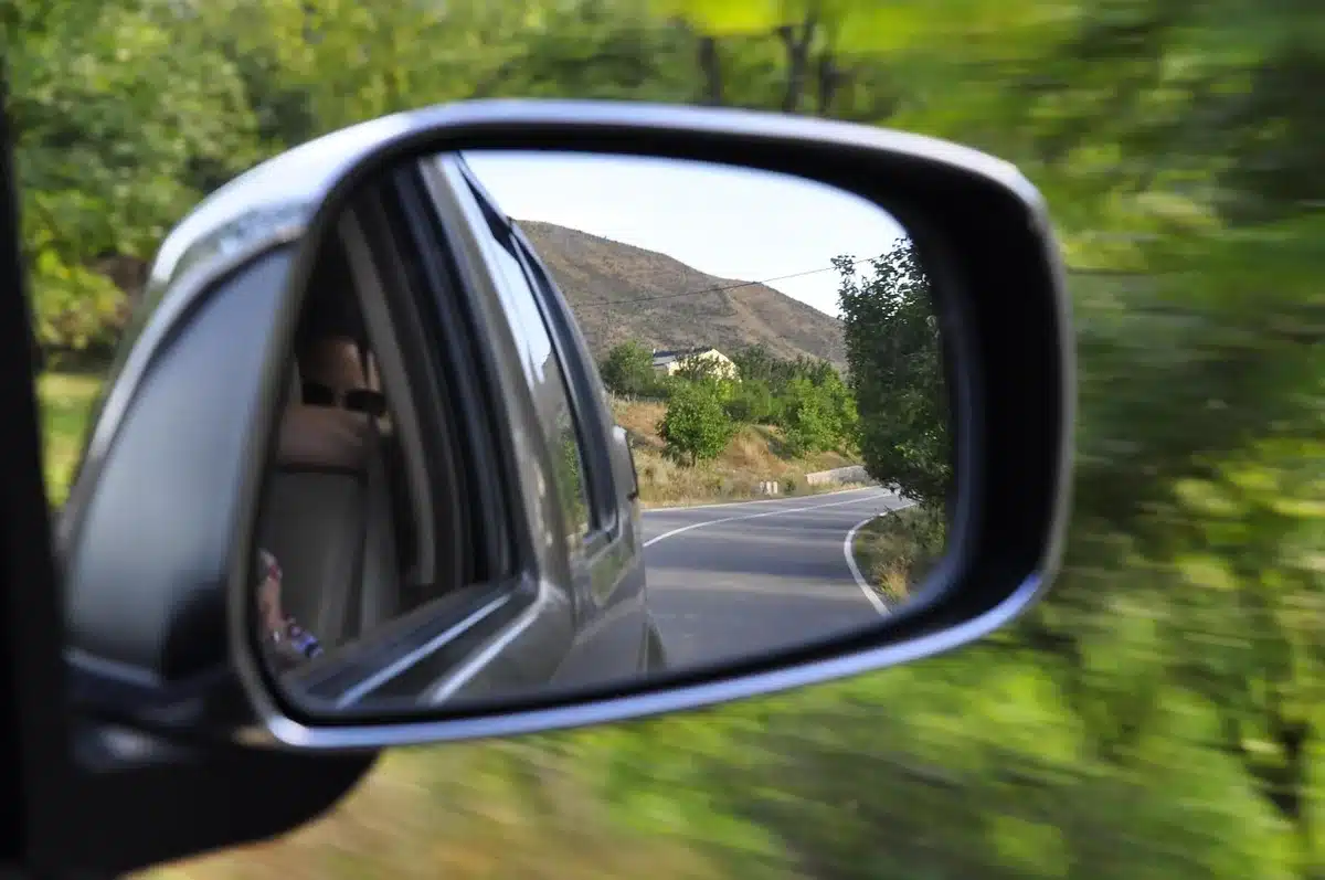 Voiture garée près d’une route secondaire avec carte et valise pour un road‑trip