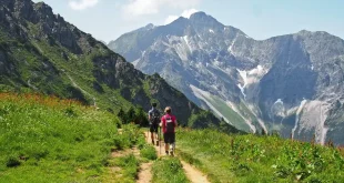 Randonneur anonyme sur un sentier alpin près d'un lac et de sommets en arrière‑plan