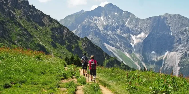 Randonneur anonyme sur un sentier alpin près d'un lac et de sommets en arrière‑plan