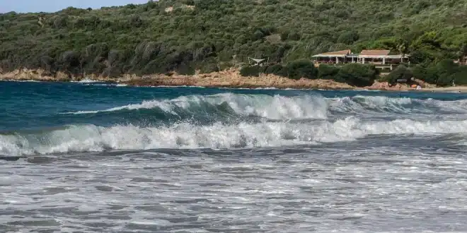 Crique corse avec eau turquoise, maquis et sentier menant à la plage
