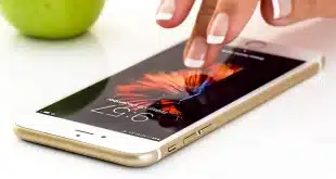 Carnet de voyage ouvert, smartphone et appareil photo sur une table, mains anonymes
