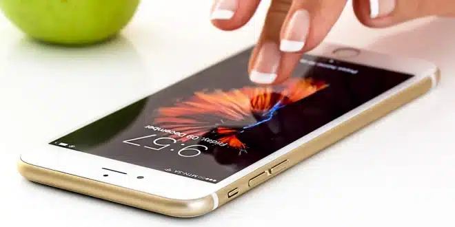 Carnet de voyage ouvert, smartphone et appareil photo sur une table, mains anonymes