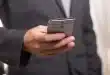Smartphone sur une table d'aéroport avec passeport et valise en arrière‑plan