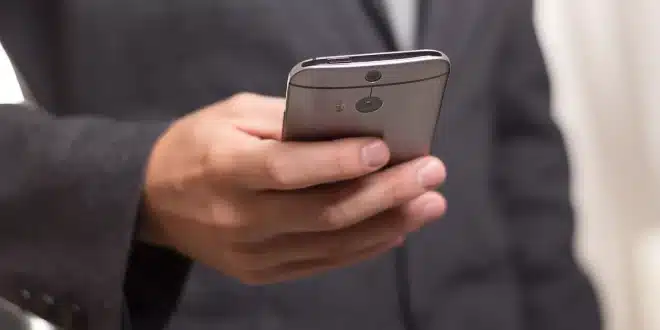 Smartphone sur une table d'aéroport avec passeport et valise en arrière‑plan