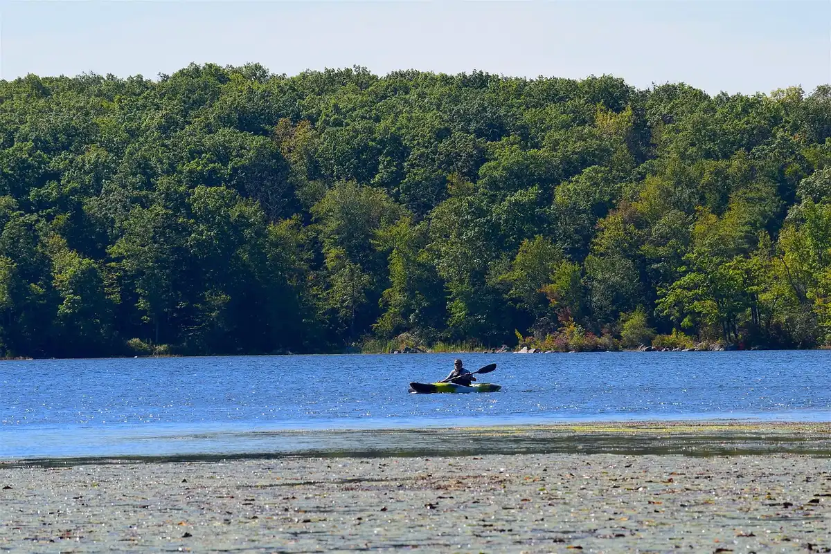 Lac de Rouffiac bordé de forêt avec plan d'eau calme et activités nautiques