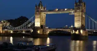 Village riverain avec pont en pierre, berges et canoës, lumière douce