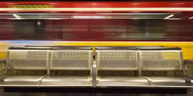 Quais d'une gare italienne avec silhouettes et valises, vue d'ensemble