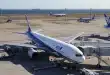 Sièges d'aéroport proches d'une grande baie vitrée, valise à côté, lumière du jour