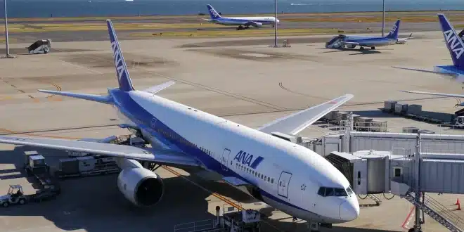 Sièges d'aéroport proches d'une grande baie vitrée, valise à côté, lumière du jour