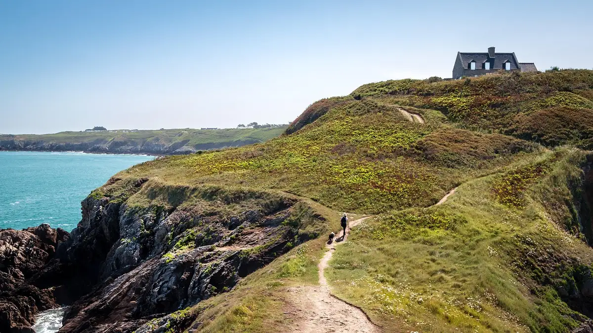 Randonneur sur un sentier côtier avec vues sur falaises et mer