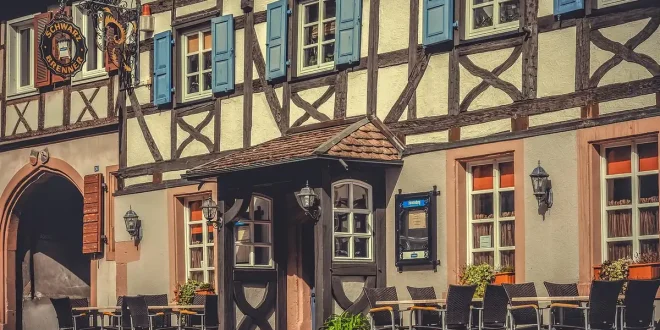 Cour ensoleillée d'un hébergement familial avec terrasse et espace de jeux près d'une lisière de forêt