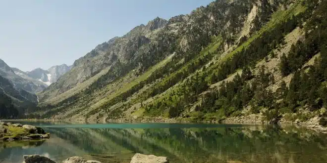 Table de pique-nique au bord d'un lac pyrénéen avec carte et gourde, en plein jour