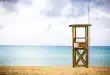 Plage de sable avec familles anonymes, tour de secours et soleil de jour