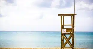 Plage de sable avec familles anonymes, tour de secours et soleil de jour