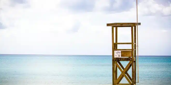 Plage de sable avec familles anonymes, tour de secours et soleil de jour
