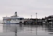 Quai ensoleillé avec ferry, carte touristique et café, îles et pins en arrière-plan
